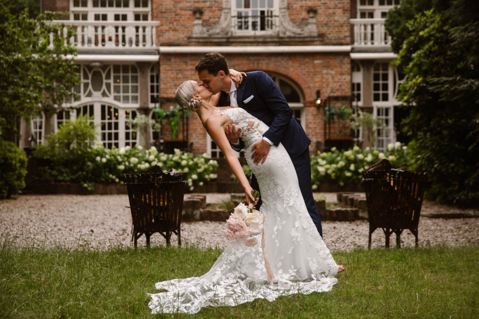 een bruid en bruidegom die elkaar kussen voor een gebouw