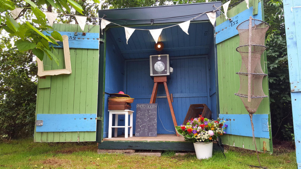een kleine groene en blauwe schuur met een fotolijst