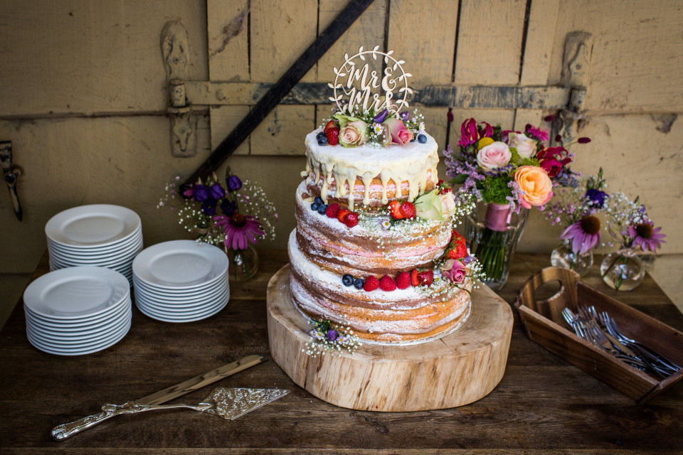 een bruiloftstaart op een houten tafel met bloemen