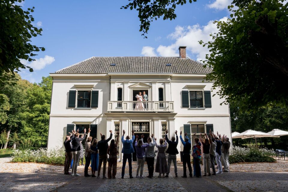 een grote groep mensen die voor een groot wit huis staan