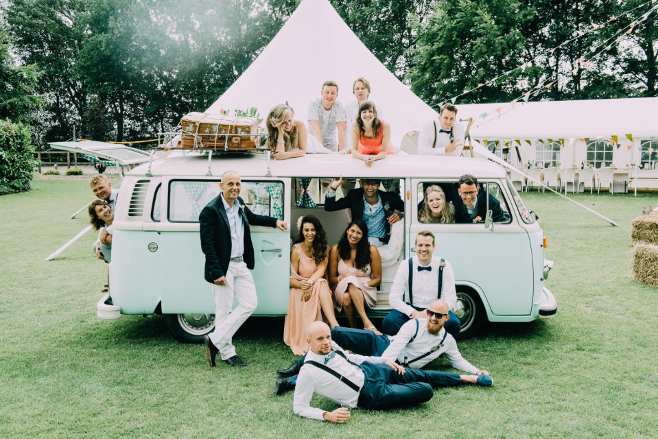 een groep mensen poseren voor een vintage busje