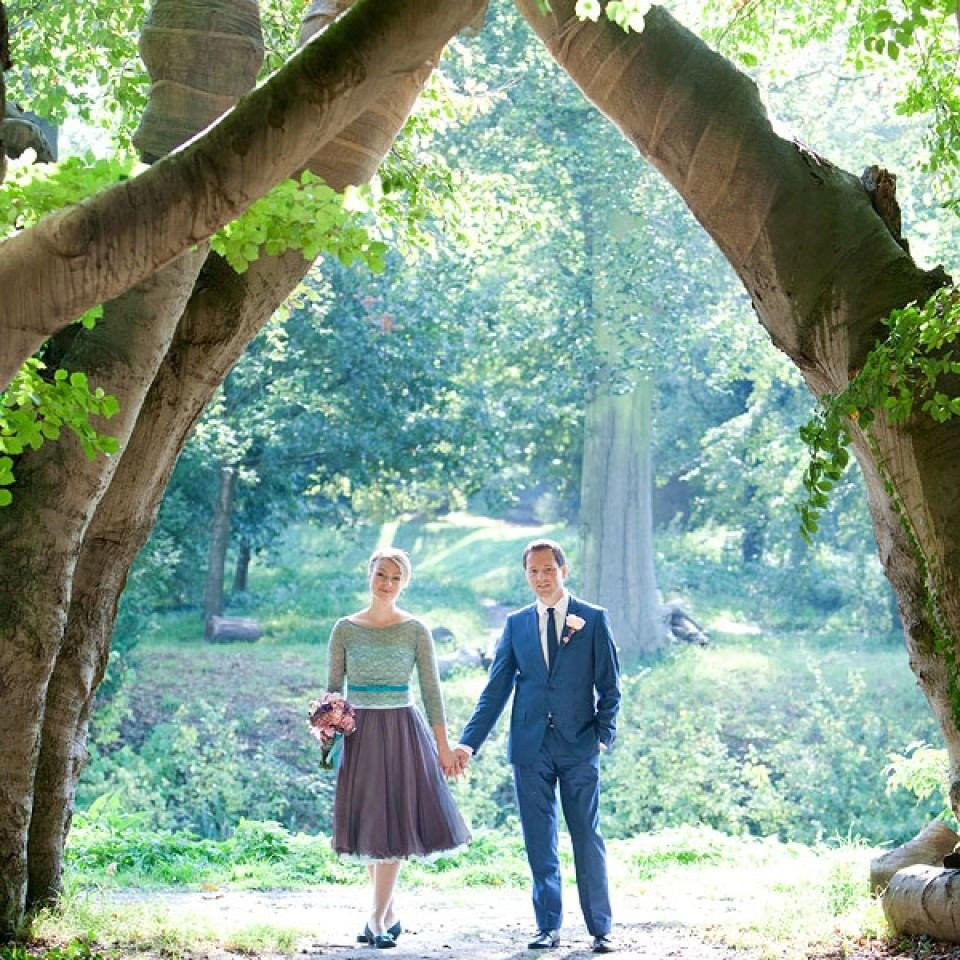 een bruid en bruidegom lopen door een doorgang in het bos