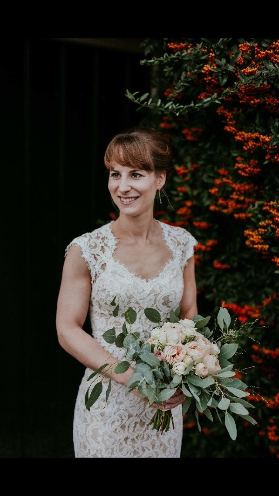 bruid in kanten trouwjurk met boeket