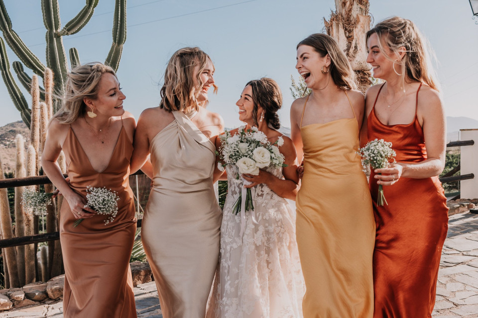 bruidsmeisjes in oranje jurken die lachen en glimlachen