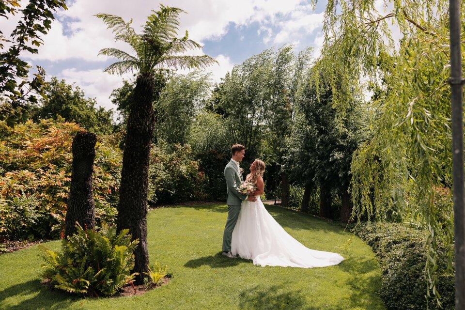 een bruid en bruidegom die poseren voor een foto in de tuin