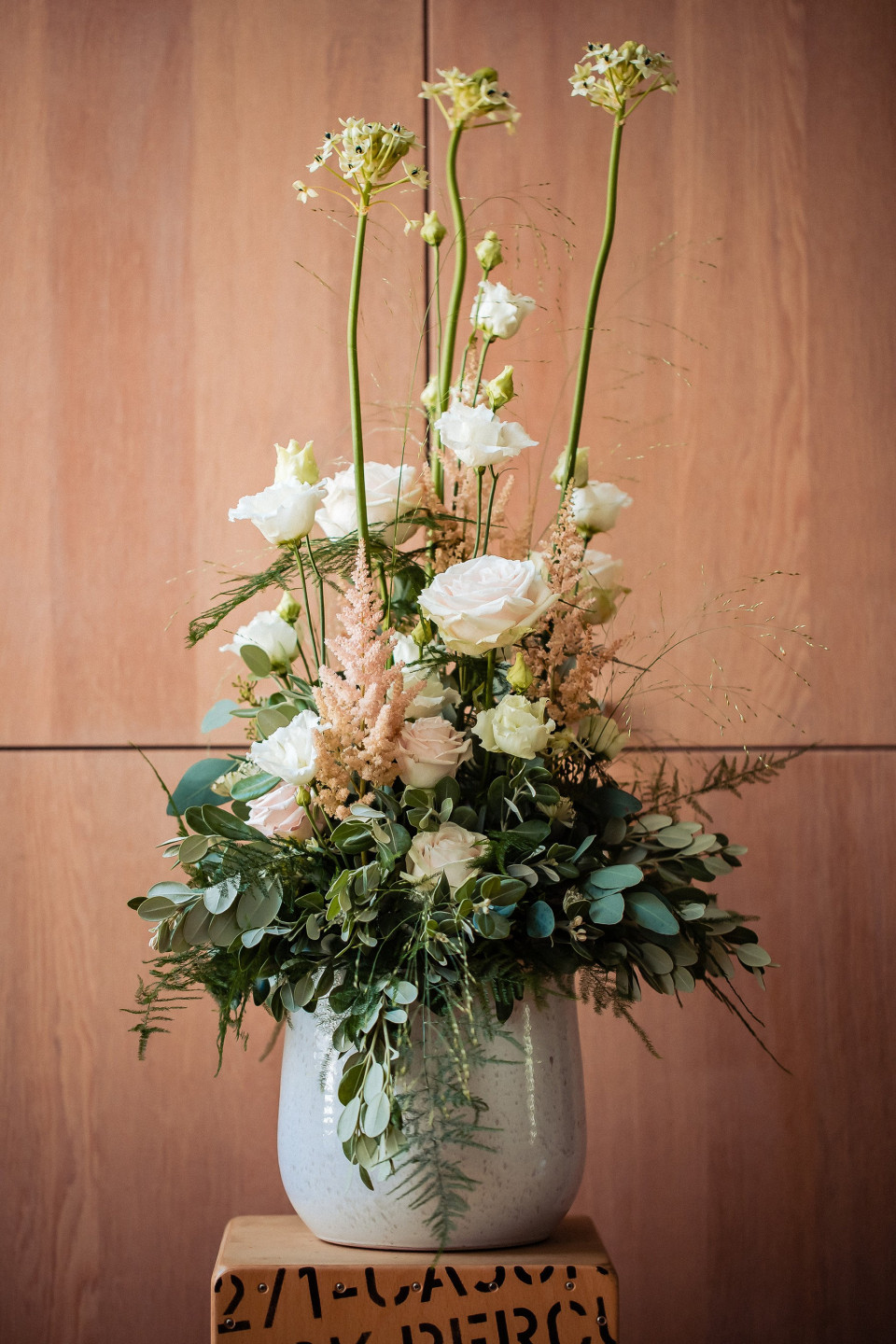 een vaas met bloemen en groen op een houten tafel