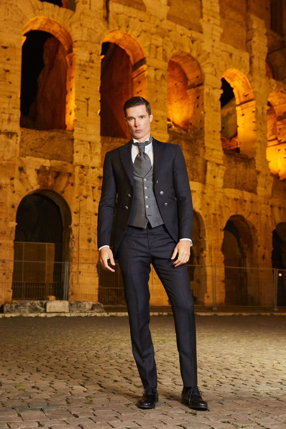 een man in pak staat voor een oud gebouw