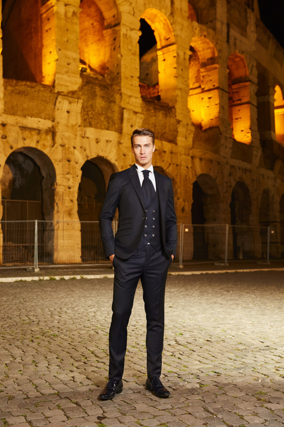 een man in pak staat voor een oud colosseum