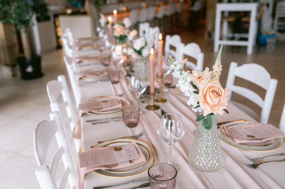 een tafel gedekt voor een trouwreceptie met roze en gouden bloemen