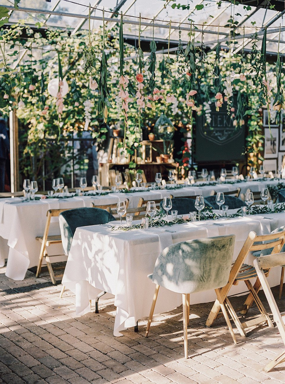 een trouwreceptie in een kas met witte tafelkleden en groene stoelen