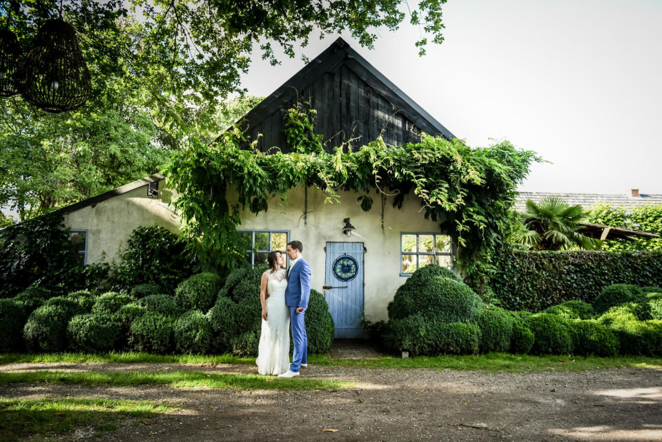 een bruid en bruidegom poseren voor een huis