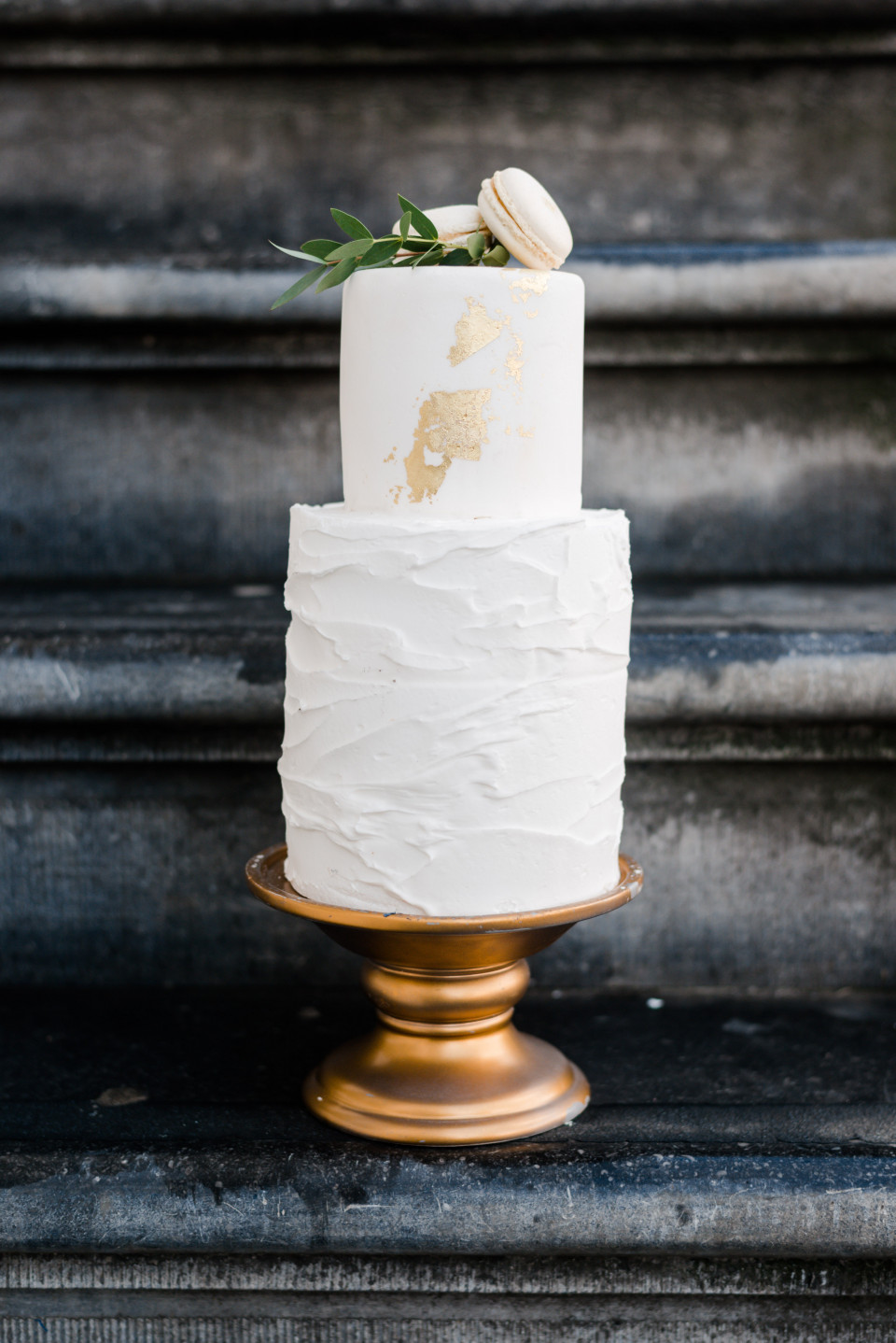 Een simpele witte bruidstaart met gouden bewerking
