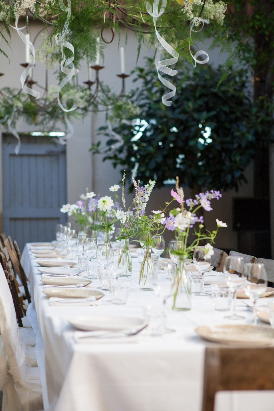 een lange tafel met wit linnen en bloemen
