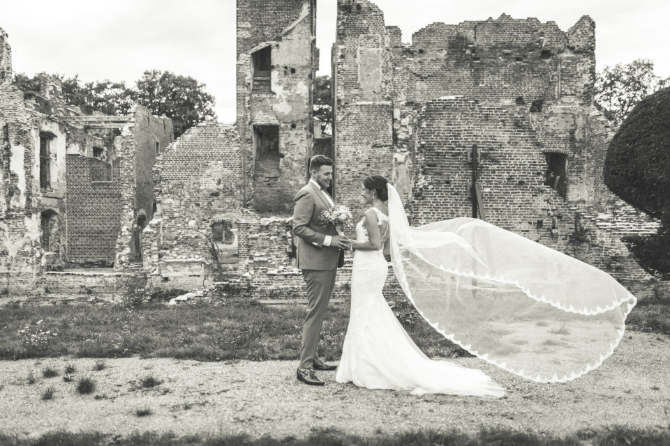een bruid en bruidegom poseren voor een oud kasteel