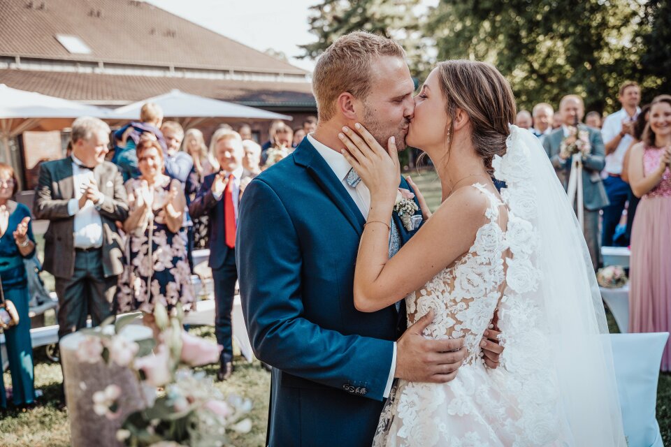 een bruid en bruidegom die voor een menigte mensen kussen