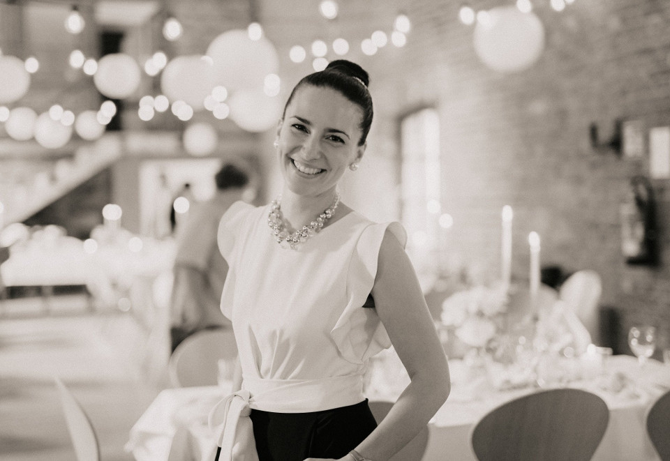 een vrouw in een witte jurk die voor tafels staat