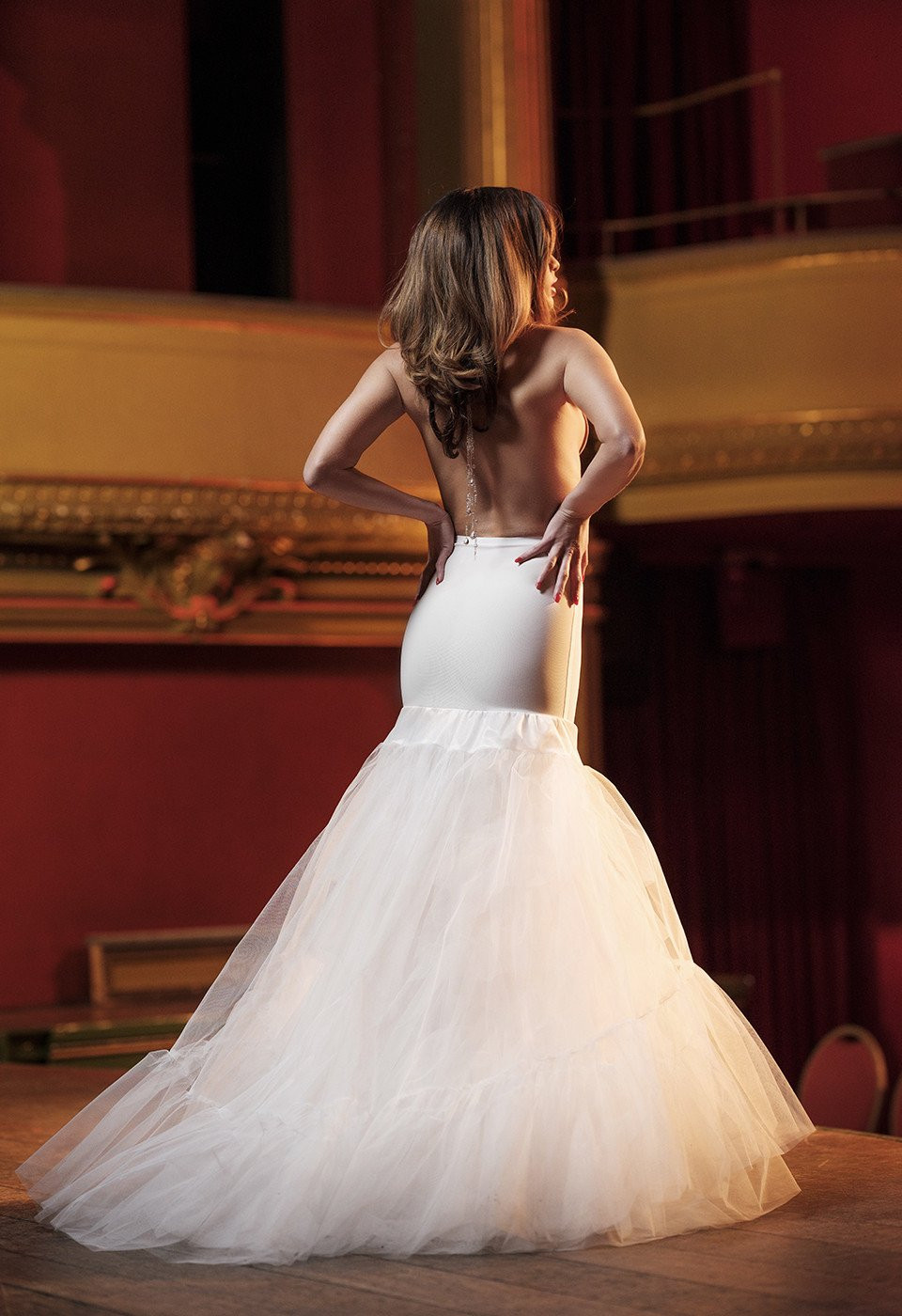 een vrouw in een trouwjurk staat op een podium