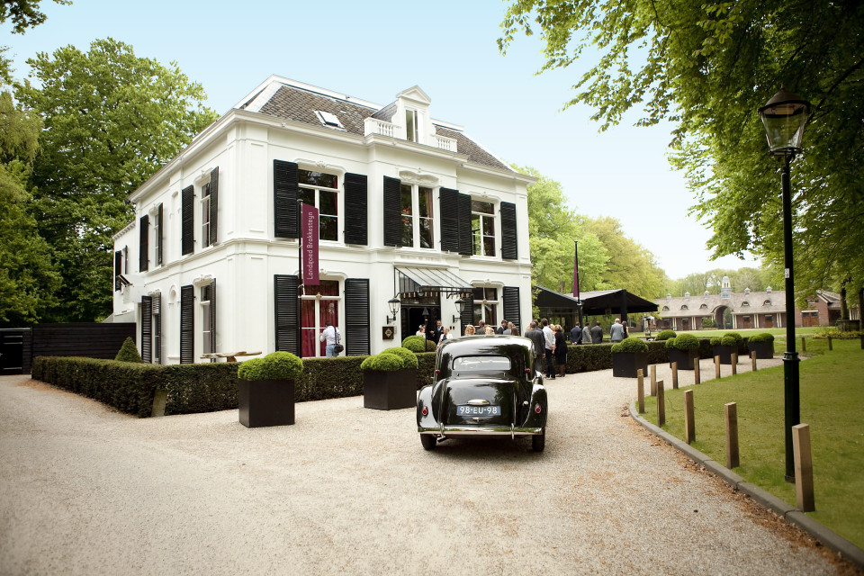 een klassieke auto geparkeerd voor een wit gebouw