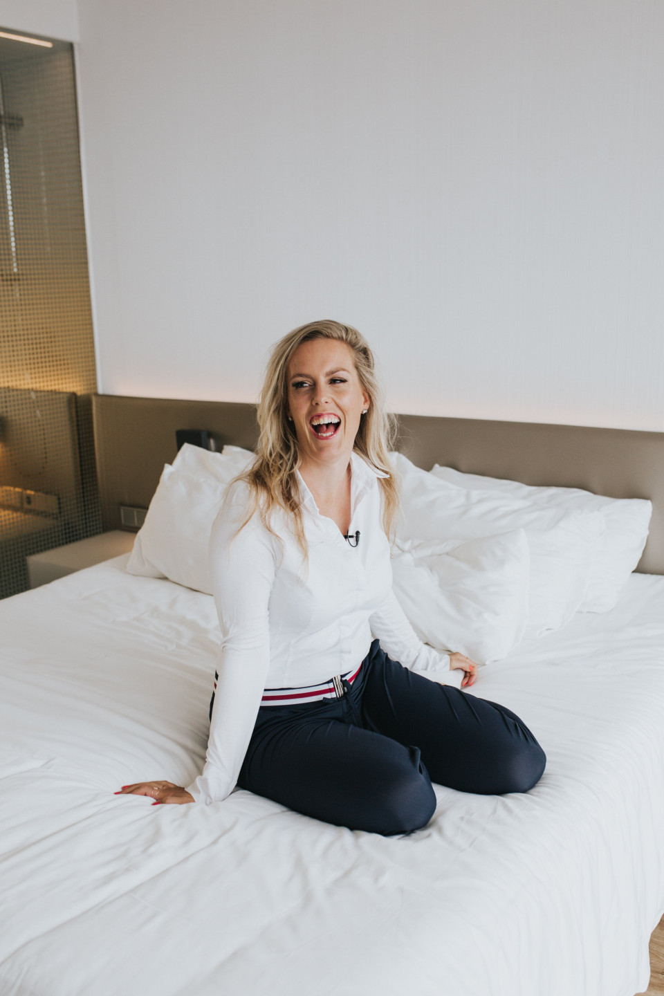 een vrouw zit op een bed in een hotelkamer