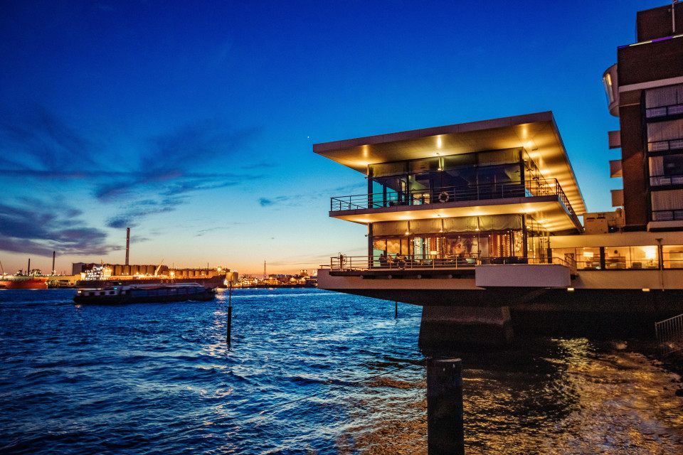 een gebouw aan het water met een blauwe lucht