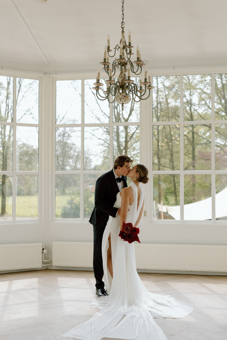 een bruid en bruidegom die elkaar kussen in een grote kamer