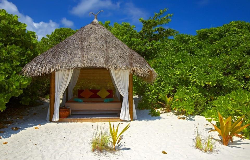 een hut met een rieten dak op een zandstrand