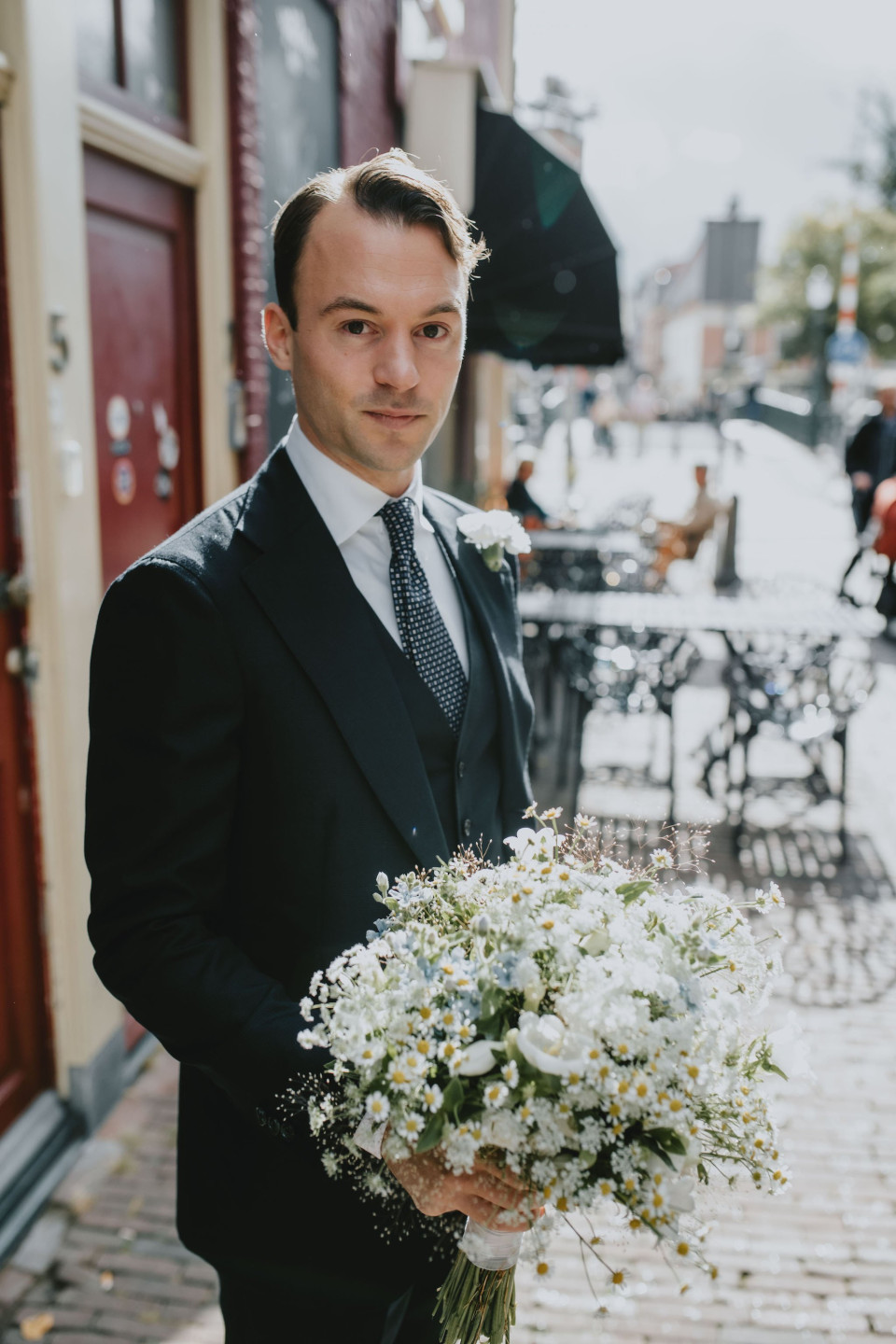 een man in een pak die een boeket bloemen vasthoudt