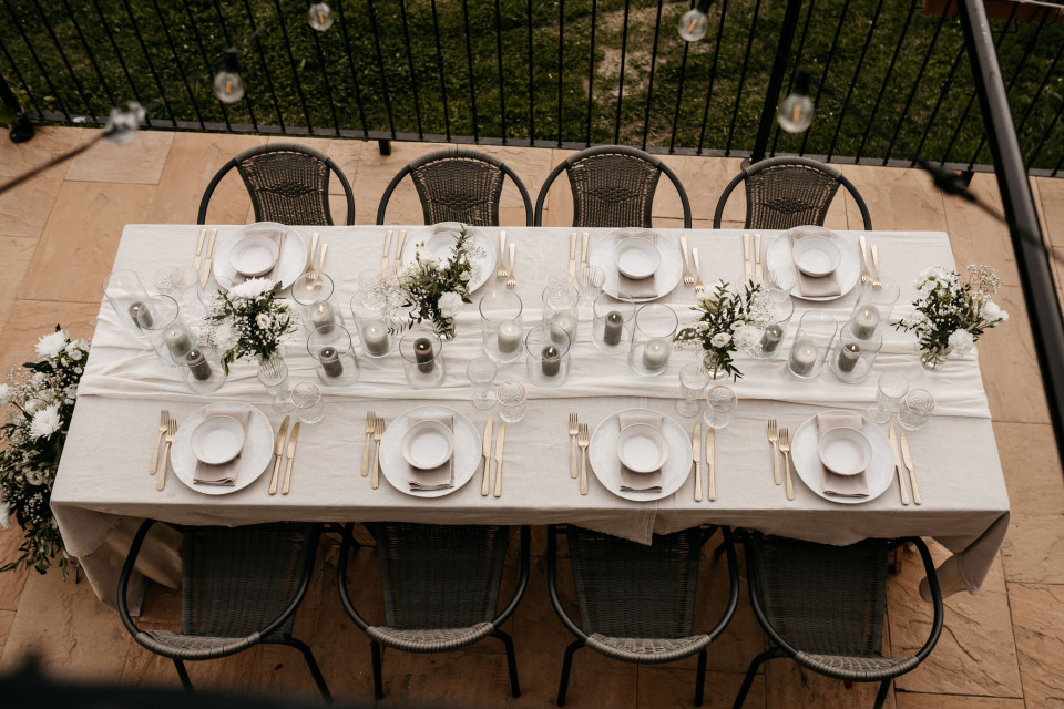 een bovenaanzicht van een eettafel met plaatsinstellingen en plaatsinstellingen op de tafel, met een hek op de achtergrond