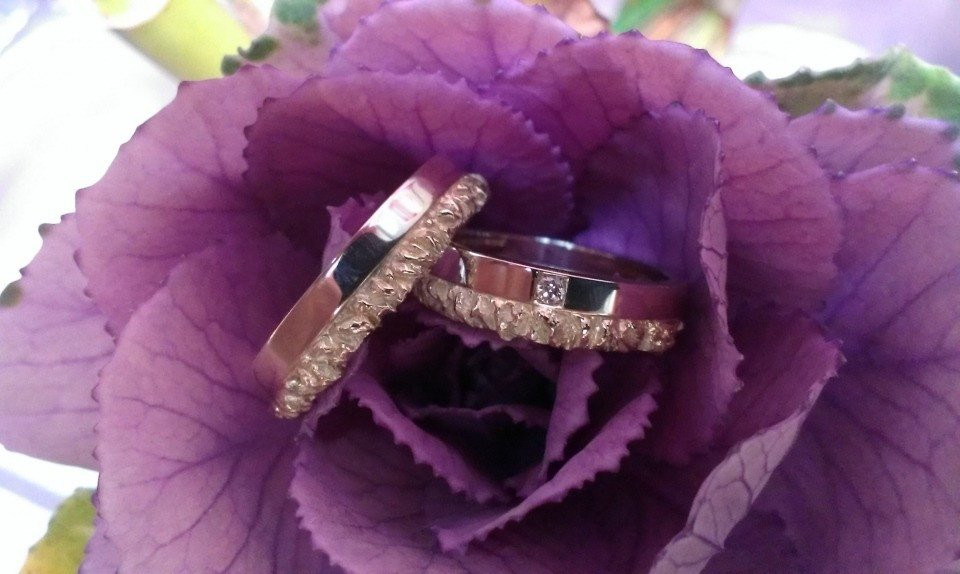 twee trouwringen bovenop paarse bloemen