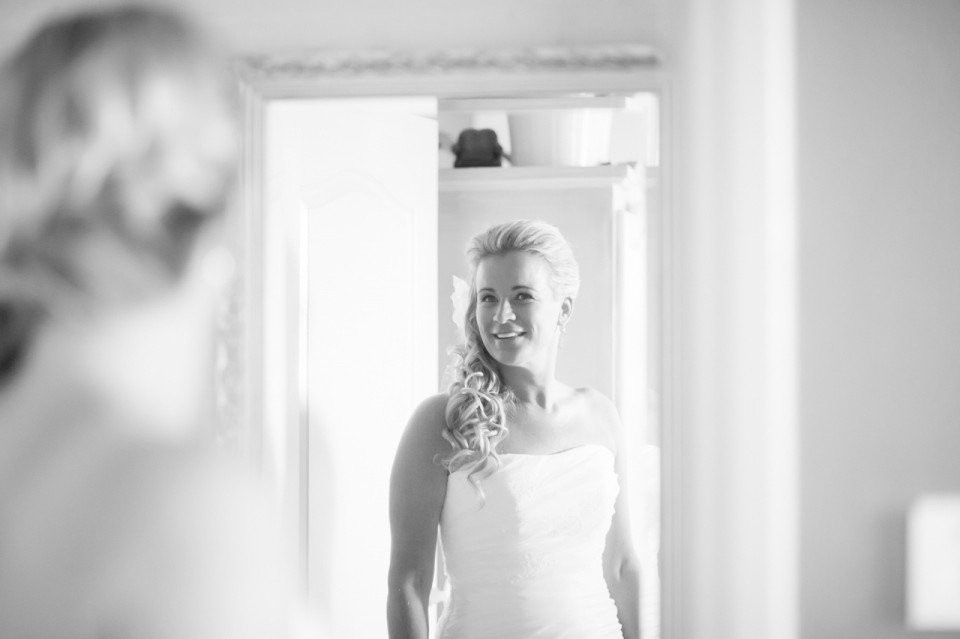 een vrouw in een trouwjurk kijkt in de spiegel