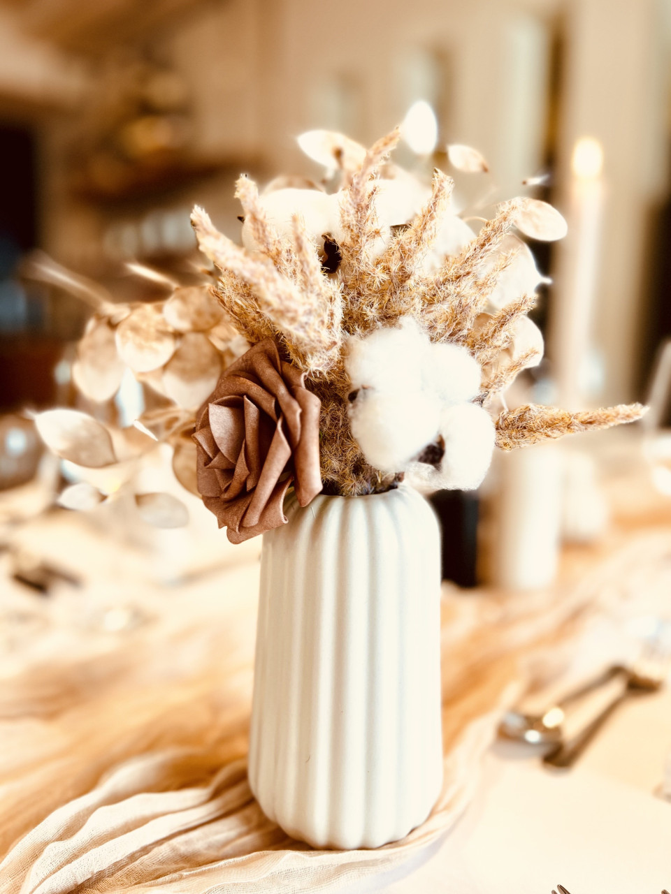 een vaas met bloemen en katoen op een tafel