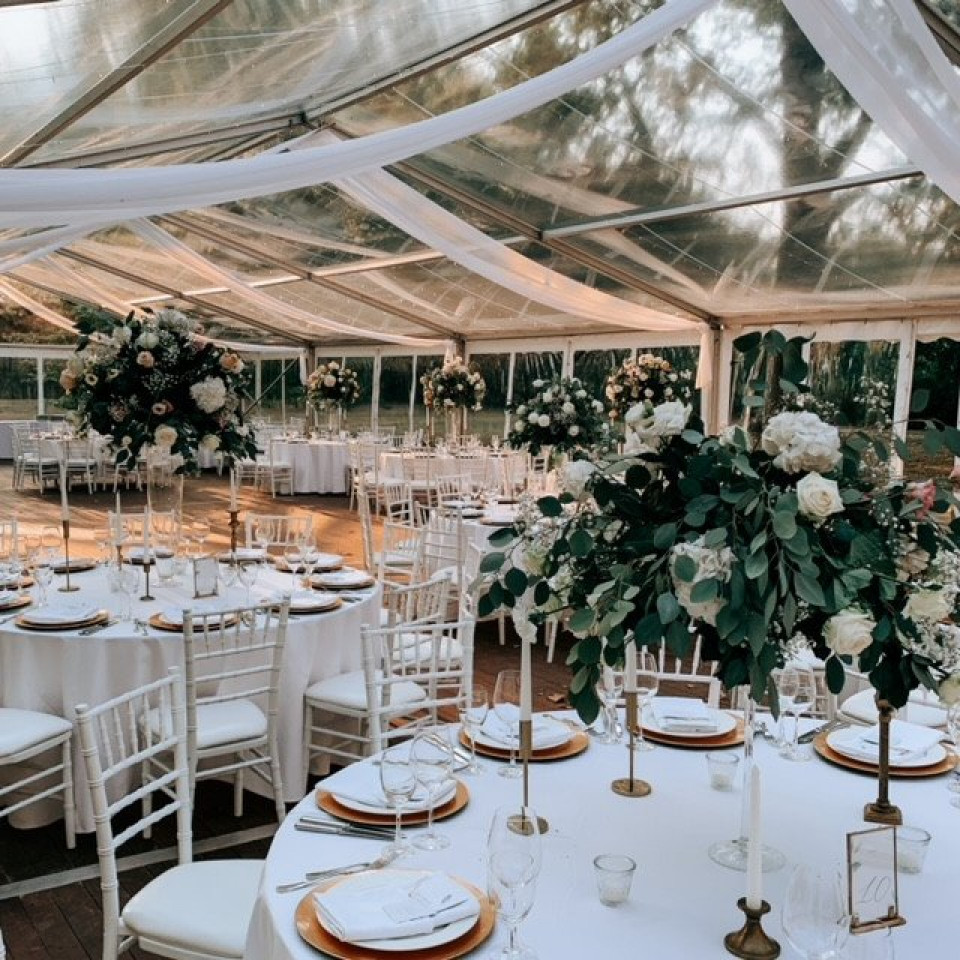 een bruiloftsreceptie in een tent met witte tafels en stoelen