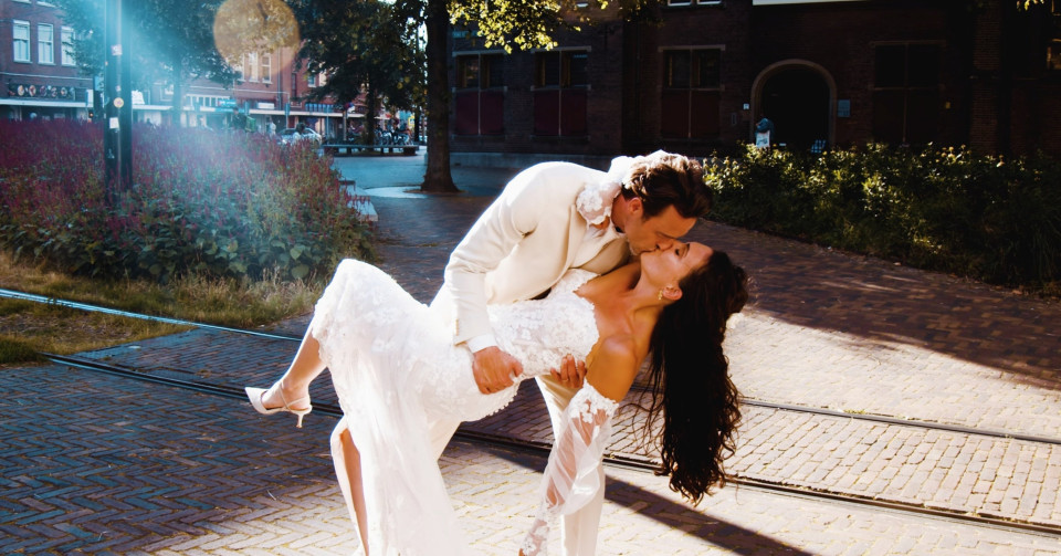 een bruid en bruidegom kussen op straat voor een gebouw