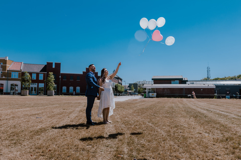 een bruidspaar dat ballonnen vasthoudt in het gras