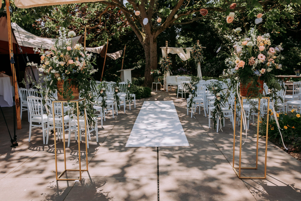 een buitenbruiloft ceremonie met witte stoelen en bloemen
