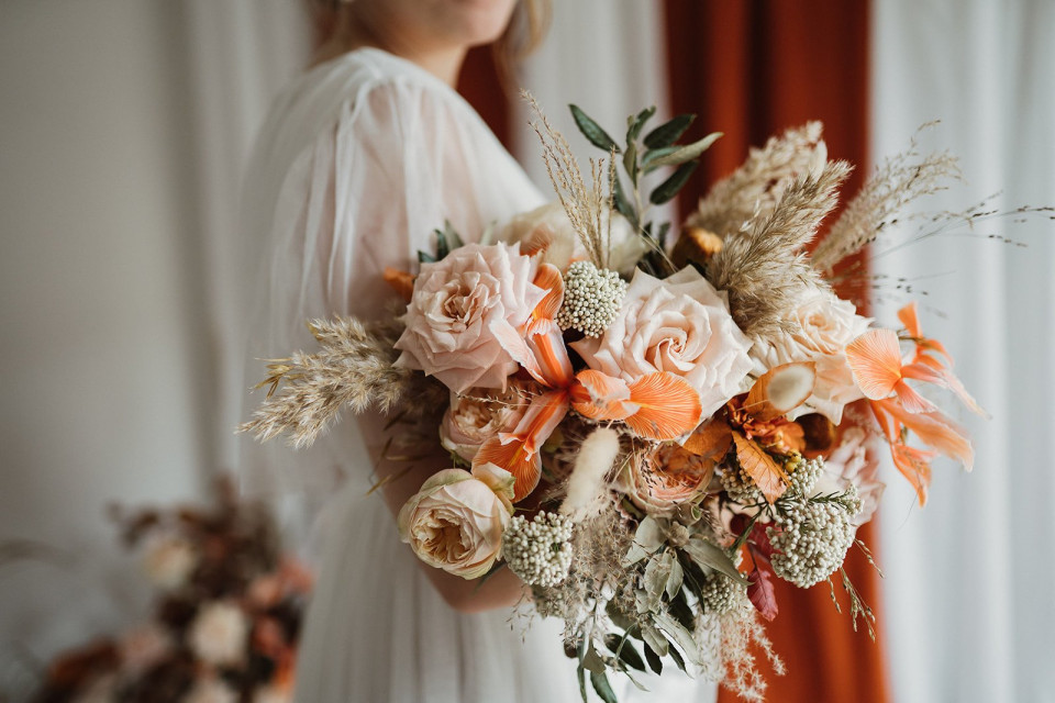 een bruid die een boeket gedroogde bloemen en groen vasthoudt