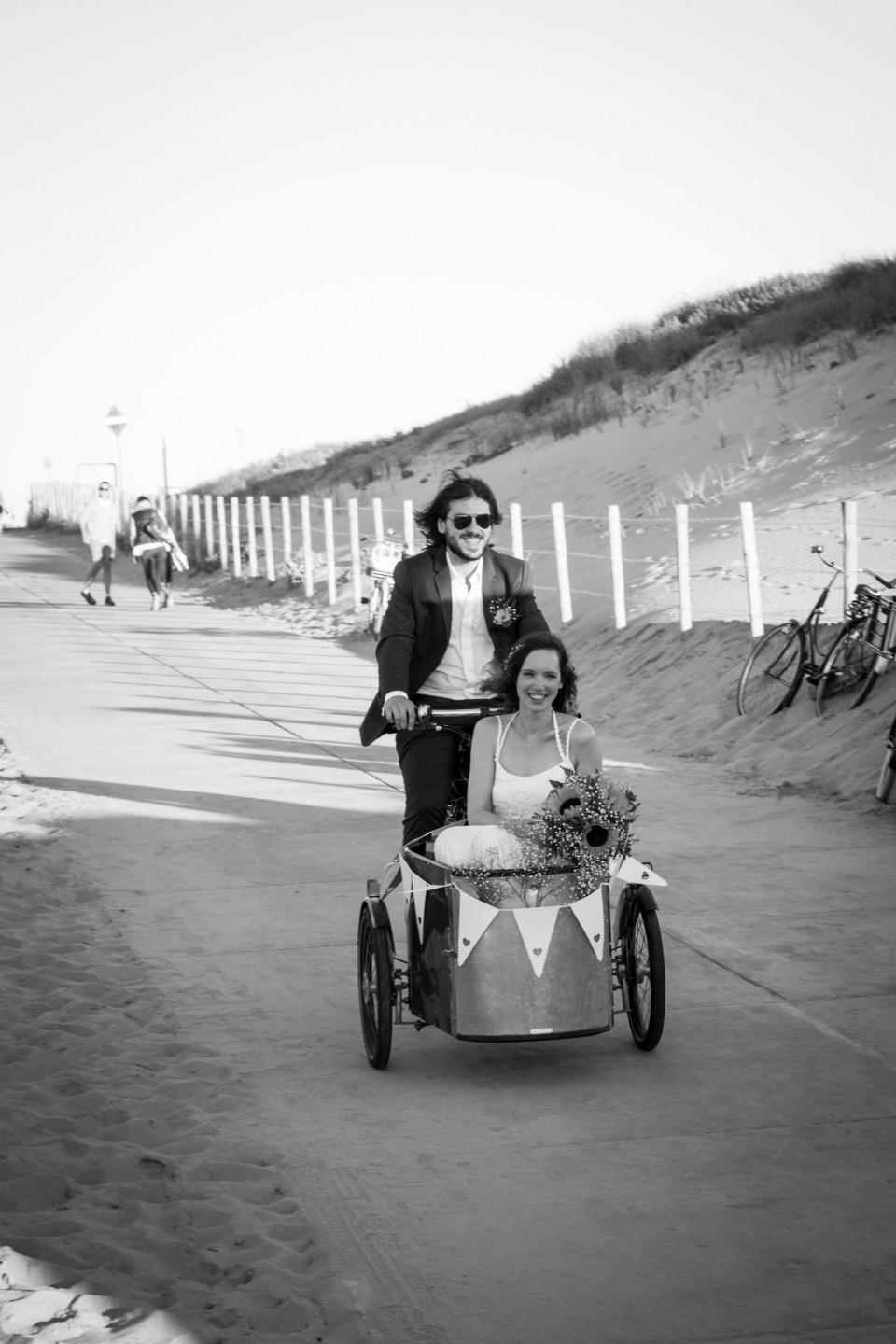 een bruidspaar rijdt in een kar op het strand