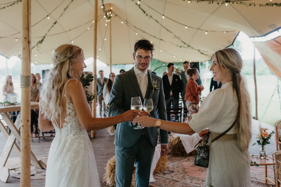 een bruid en bruidegom die toosten in een tent