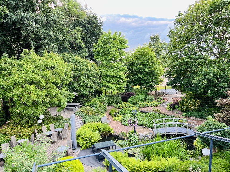 een tuin met een brug en banken