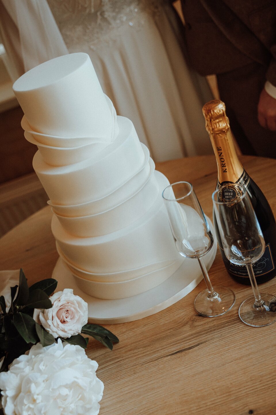 een bruidstaart met een fles champagne ernaast