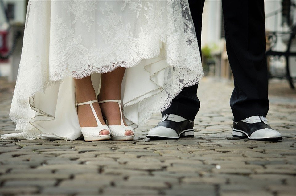 een bruid en bruidegom dragen witte schoenen en trouwjurk