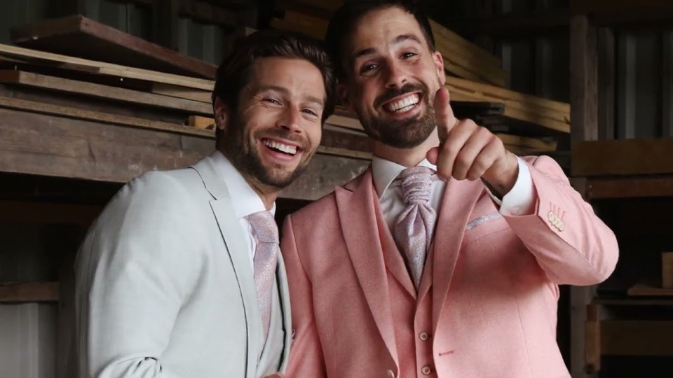 twee mannen in roze pakken poseren voor de camera