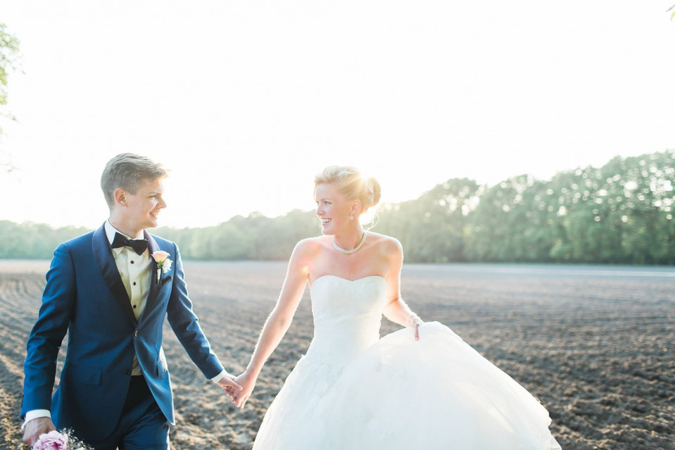 een bruid en bruidegom die in een veld lopen