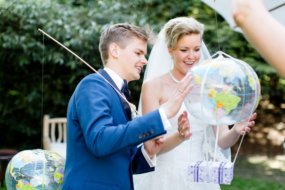 een bruid en bruidegom die een globe in hun handen vasthouden