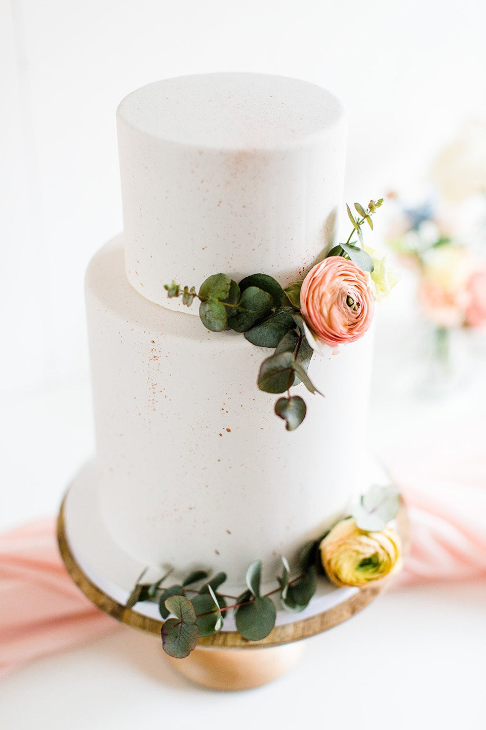 een witte taart met roze bloemen en groen