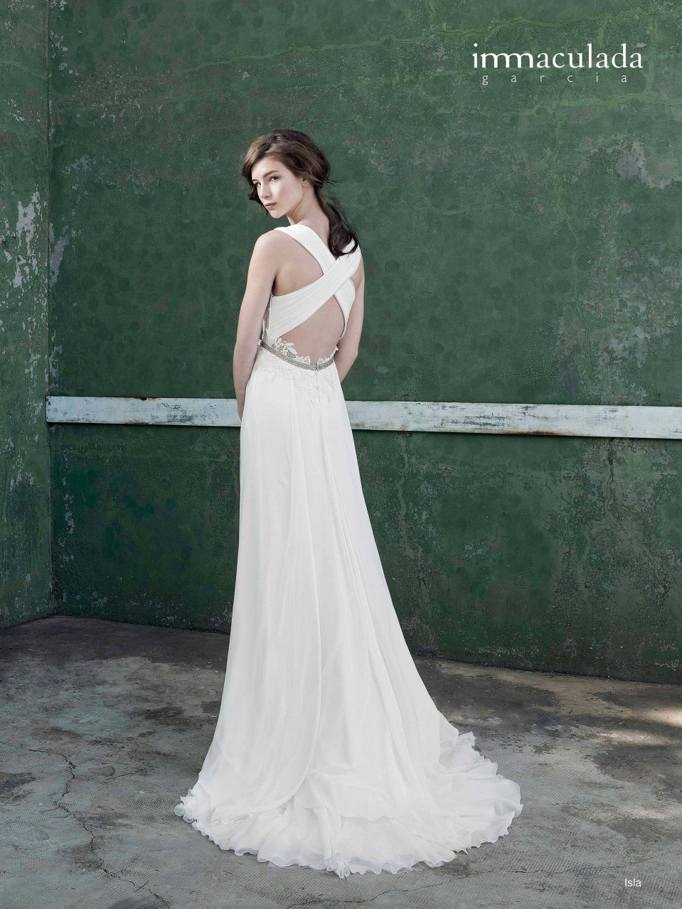 een vrouw in een witte trouwjurk die voor een groene muur staat