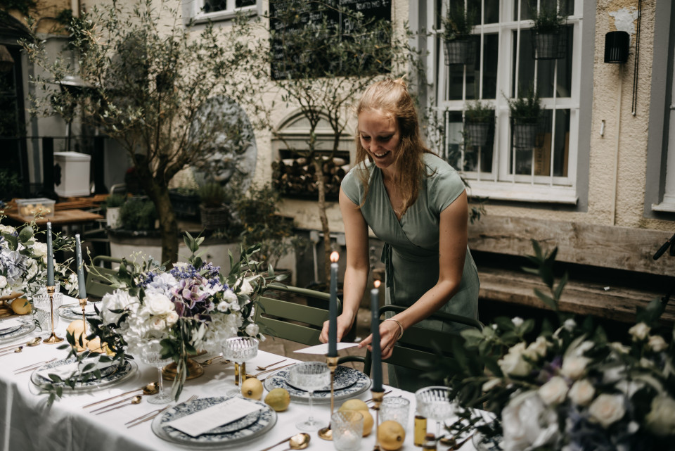 een vrouw die een tafel dekt met bloemen en kaarsen