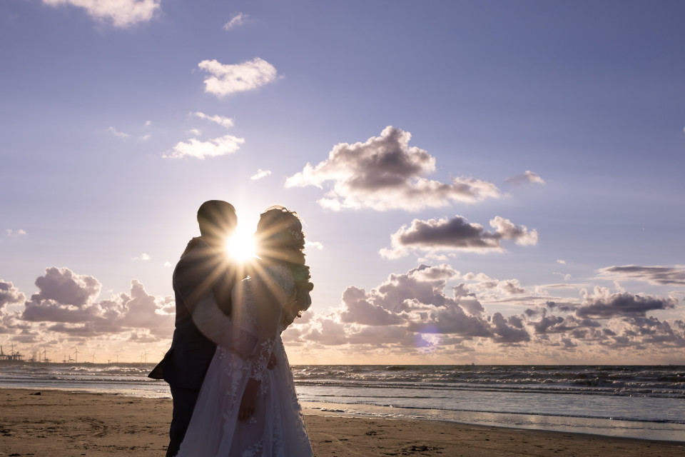 een bruid en bruidegom omhelzen op het strand bij zonsondergang