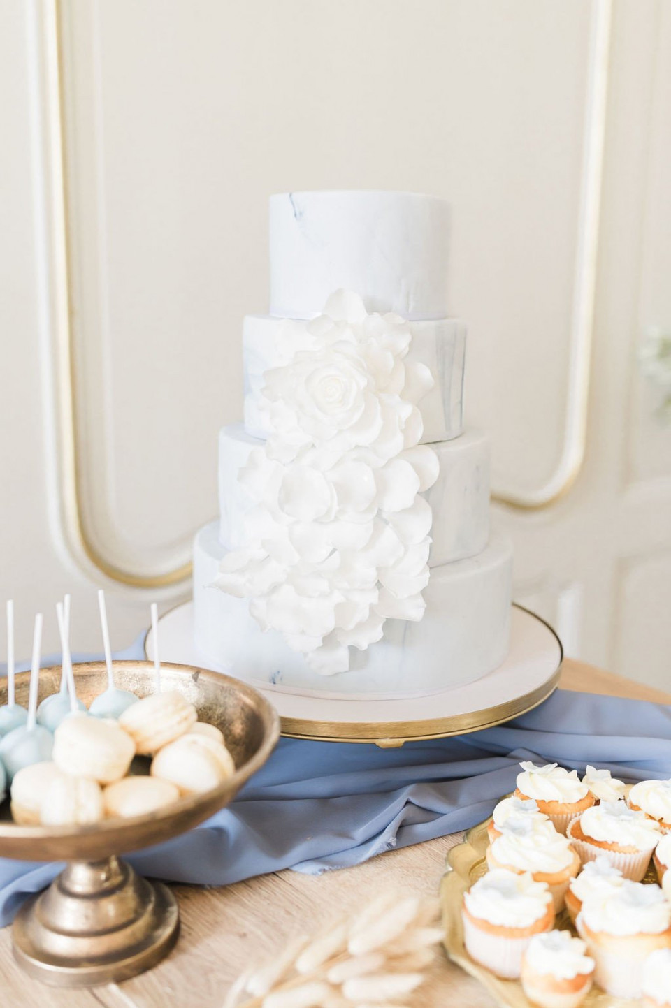 een blauwe tafel met een witte taart en cupcakes