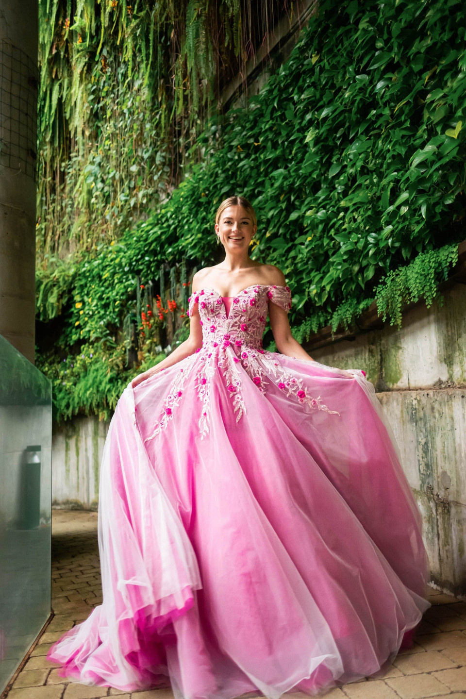 een vrouw in een roze baljurk poseert voor een foto